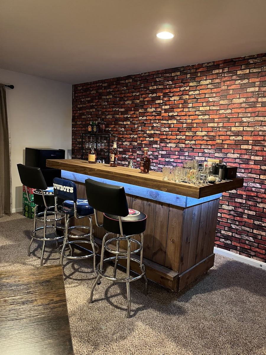Wood bar with blue accent lighting, stools and a brick-pattern wall