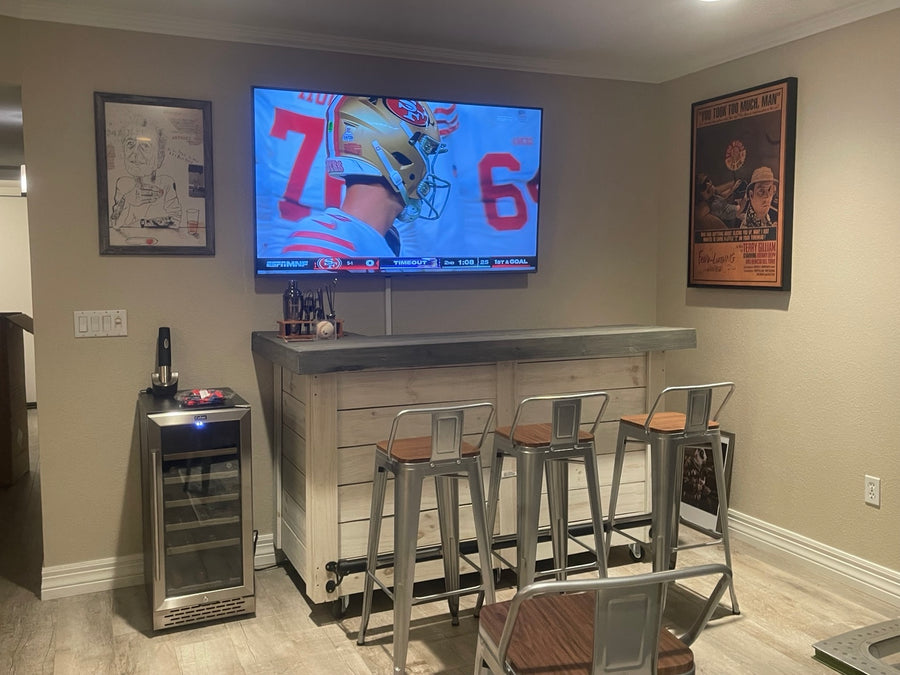 Whitewashed wood bar with a gray top, metal stools and a wall-mounted television