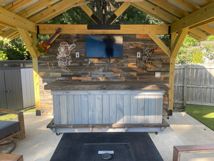 Gray wood bar with a dark top beneath a timber gazebo