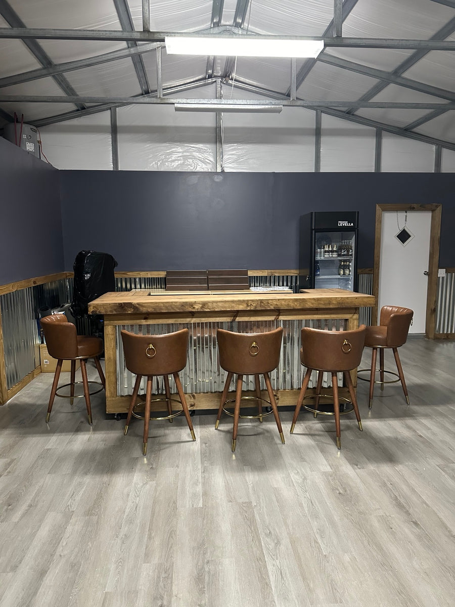 Wood and corrugated metal bar with five brown stools in a finished garage