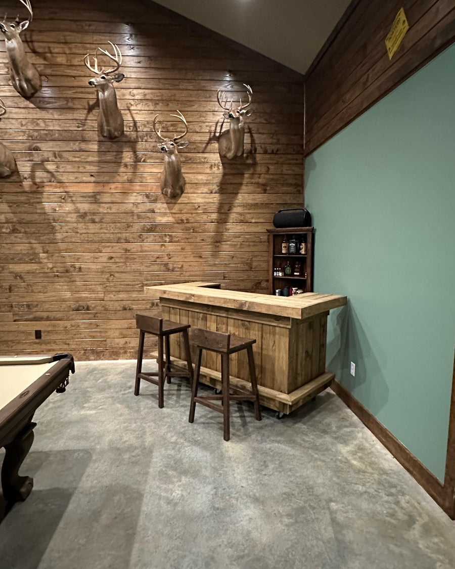 Natural wood bar with two wooden stools in a wood-paneled game room