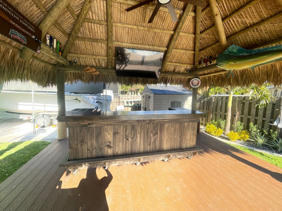 Dark wood straight bar beneath a thatched roof on a wooden deck