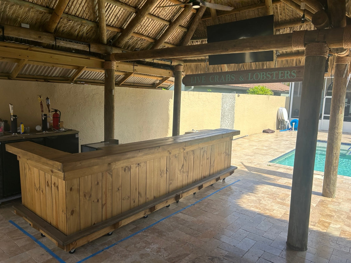 Long natural wood L-shaped bar on a covered patio beside a pool