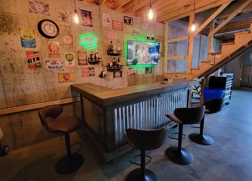 Wood and corrugated metal L-shaped bar with dark stools in a basement