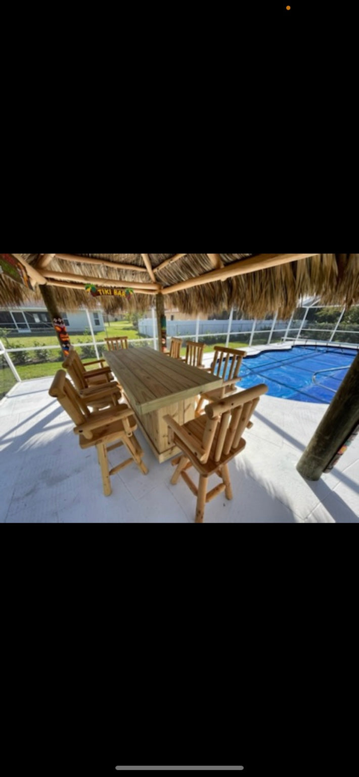 Natural wood bar surrounded by wooden stools beneath a thatched poolside shelter