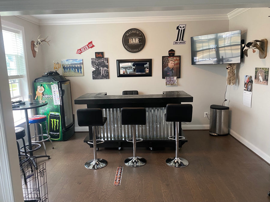 Dark-framed corrugated metal bar with three black stools in a home lounge