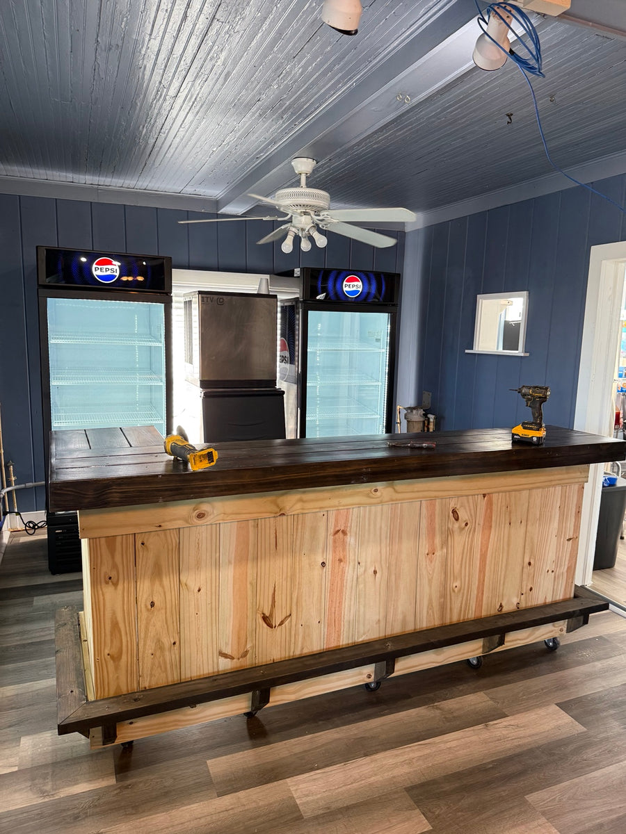 Long natural wood bar with a dark countertop in a blue game room