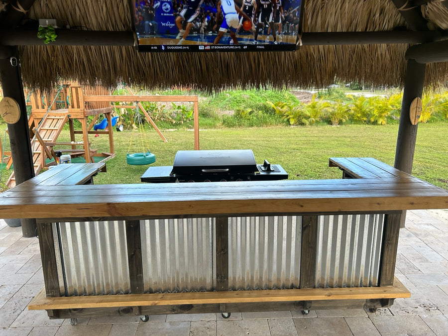 Wood-framed corrugated metal bar beneath a thatched roof with a television