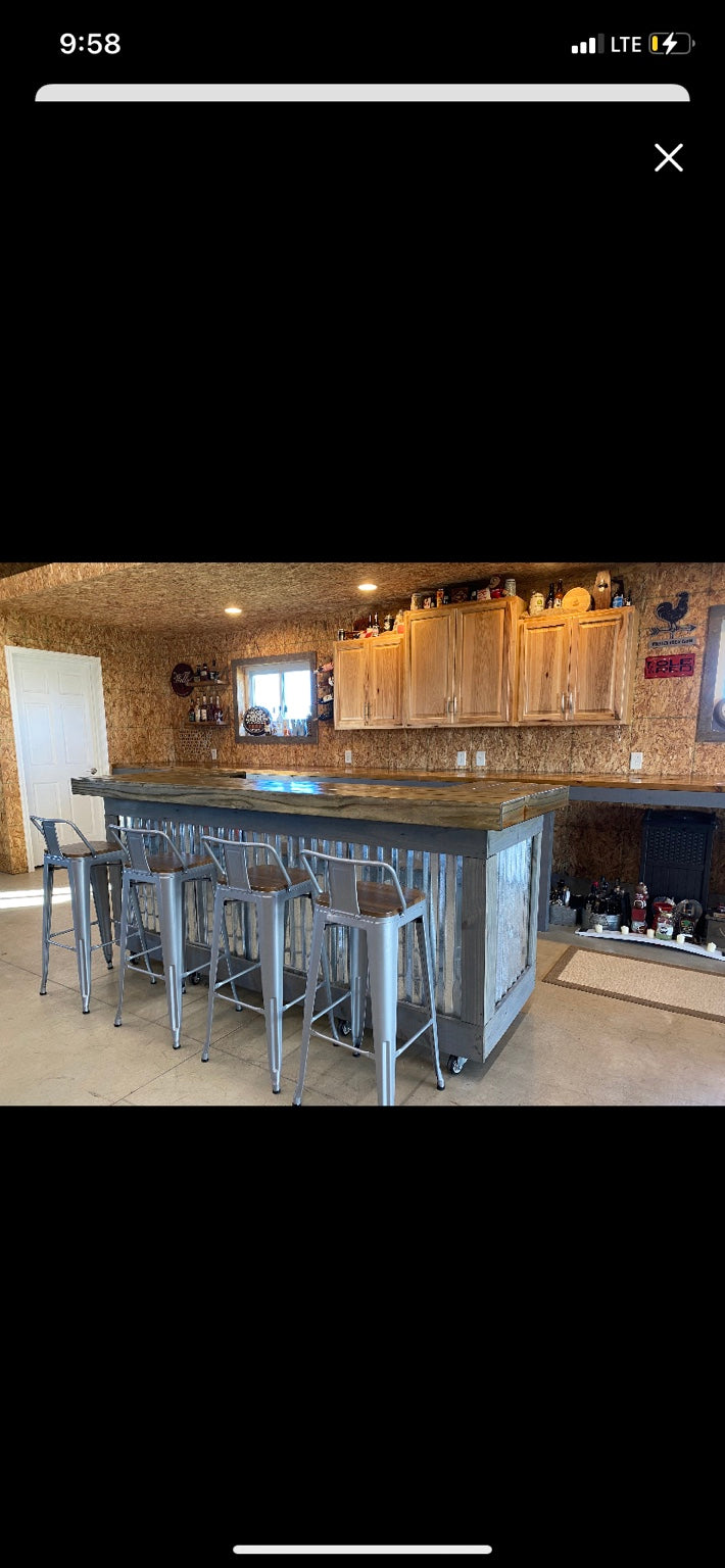 Gray-framed metal-front bar with silver stools and wood cabinets behind it
