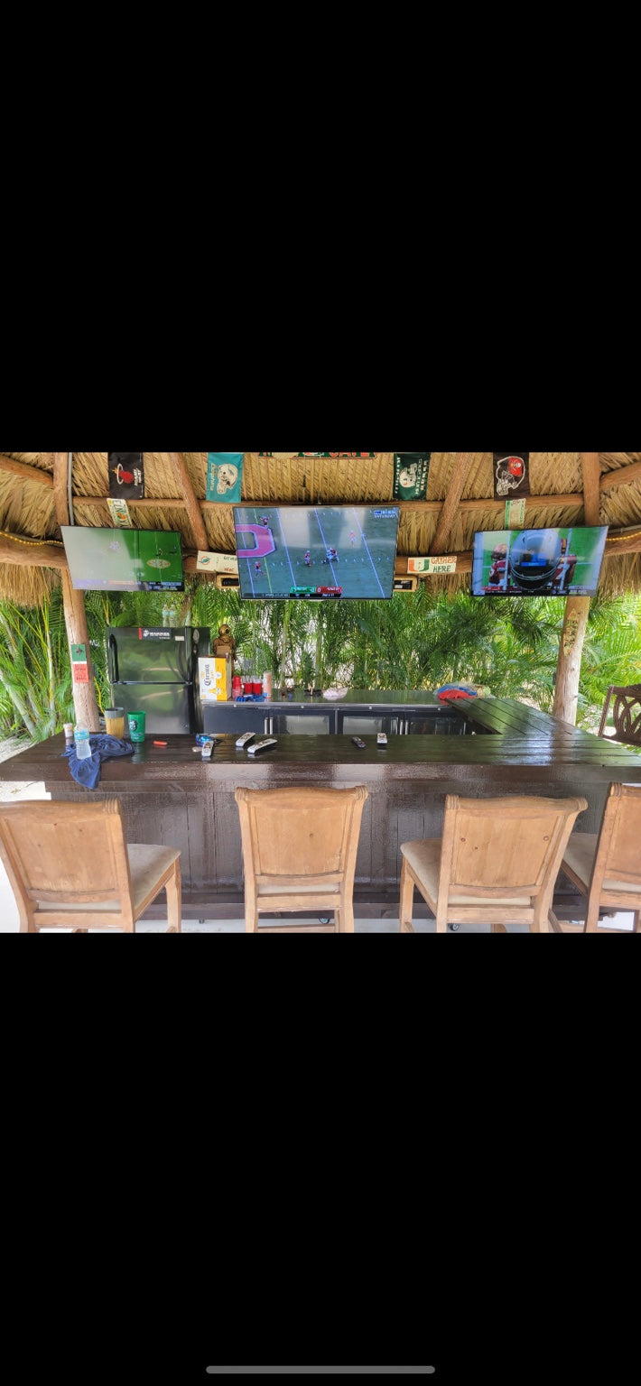 Outdoor bar and woven stools beneath a large thatched shelter