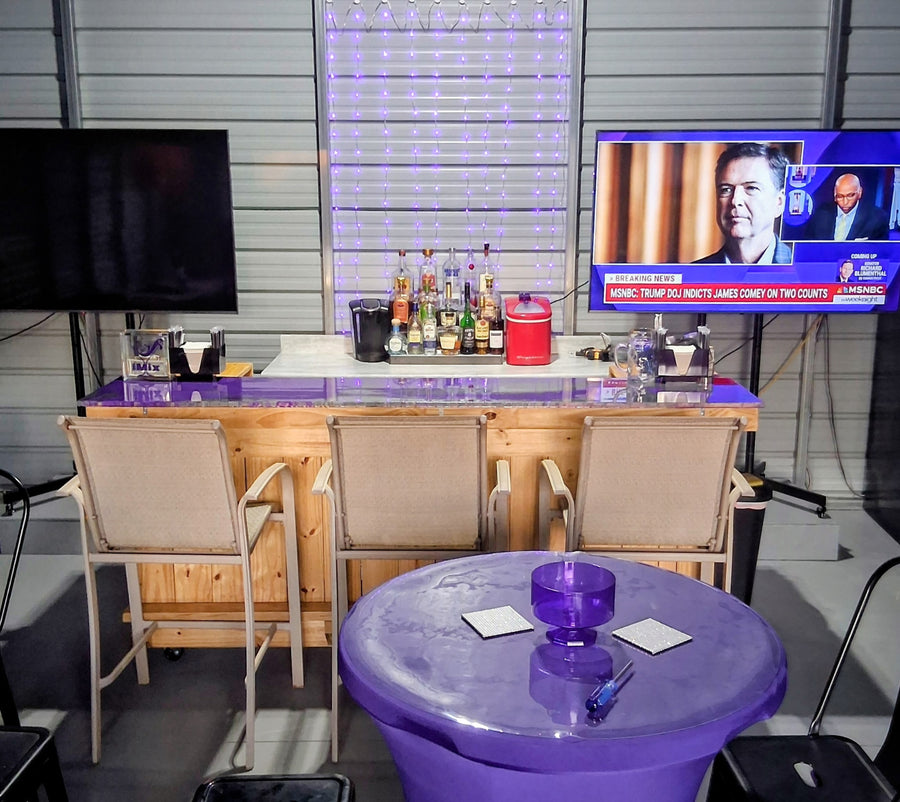 Light wood bar with purple accent lighting and cream stools in a metal-walled room