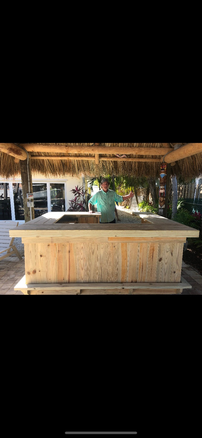 Natural wood straight bar beneath a thatched roof in an outdoor gathering area