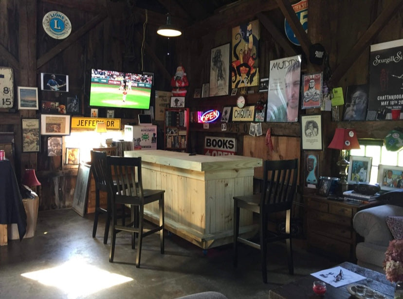 Natural wood bar with dark chairs inside a wood-paneled barn lounge