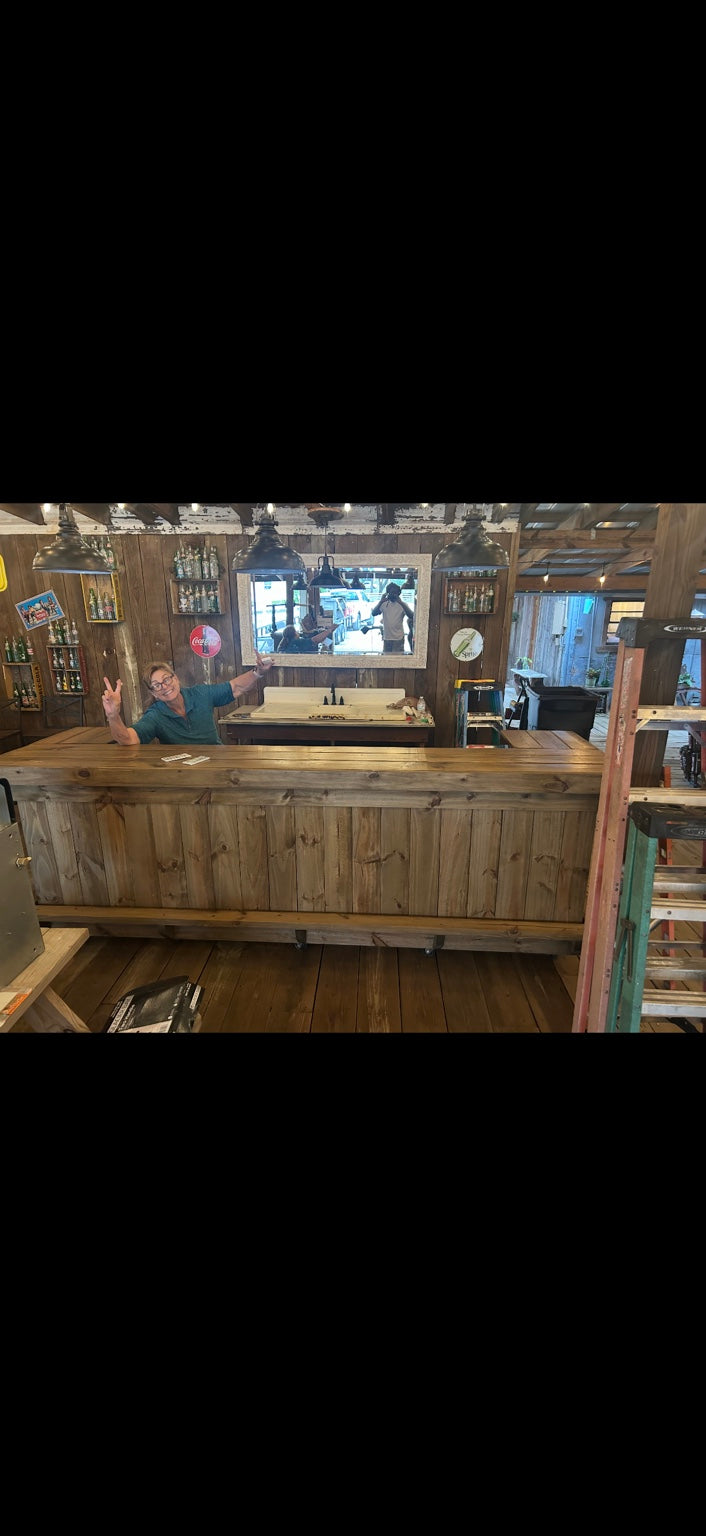 Customer standing behind a long wood bar in a rustic gathering room